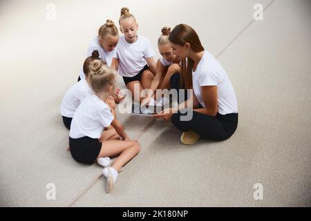 Bambine, atleti di ginnastica principianti che fanno esercizi con attrezzature di ginnastica in palestra sportiva, al coperto. Concetto di studio, realizzazioni, abilità Foto Stock