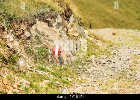 Segnaletica rossa e bianca (segnavia) dipinta su una pietra lungo un sentiero escursionistico nelle Alpi austriache. Carinzia, Alpi Carniche, confine Italia-Austria. Foto Stock
