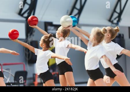 Gruppo di bambini, bambine, atleti di ginnastica per principianti in uniforme sportiva all'allenamento in palestra sportiva, al coperto. Concetto di sport, realizzazioni Foto Stock