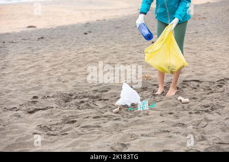 Raccolti la spiaggia femminile di pulizia del volontario irriconoscibile da immondizia Foto Stock