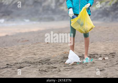 Raccolti la spiaggia femminile di pulizia del volontario irriconoscibile da immondizia Foto Stock