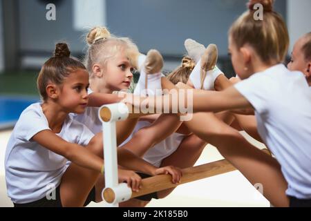 Bambine, atleti di ginnastica principianti che fanno esercizi con attrezzature di ginnastica in palestra sportiva, al coperto. Concetto di studio, realizzazioni, abilità Foto Stock