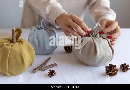 primo piano delle mani femminili che fanno le zucche del tessuto Foto Stock