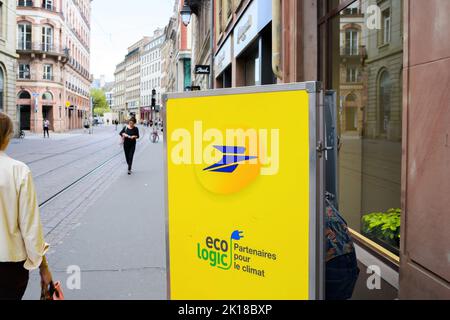 Strasburgo, Francia - 9 settembre 2022: Vista posteriore del lavoratore postale alla ricerca di pacchi lettera nel suo carrello della bici elettrica consegna pacchi Foto Stock