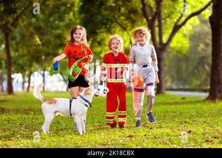 I bambini trick o trattare in costume di Halloween. I bambini in coloratissima vesti con secchio di caramelle sulla strada suburbana. Il ragazzino e la ragazza trick o trattare Foto Stock