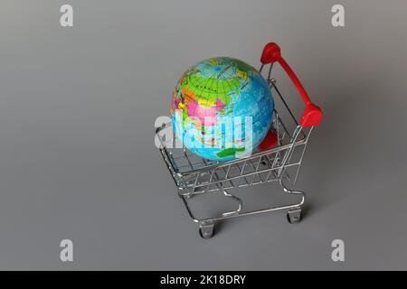 Mercato globale, concetto di mercato internazionale. Mini carrello e globo su sfondo grigio Foto Stock