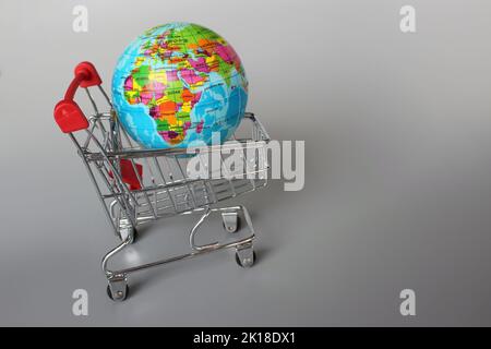 Mercato globale, concetto di mercato internazionale. Mini carrello e globo su sfondo grigio Foto Stock