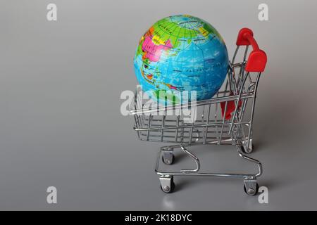 Mercato globale, concetto di mercato internazionale. Mini carrello e globo su sfondo grigio Foto Stock