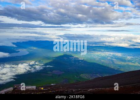 Rifugi sulle pendici del Monte Fuji con grande ombra che domina il paesaggio sullo sfondo Foto Stock