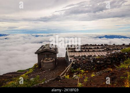 Rocce sul tetto di rifugi di montagna sopra le nuvole sul sentiero ascendente Mt. Fuji Foto Stock