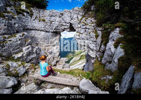 Escursionista femminile che gode della vista attraverso la cosiddetta Loserfenster, un arco di roccia sul monte Loser, Ausseer Land, Stiria, Austria Foto Stock