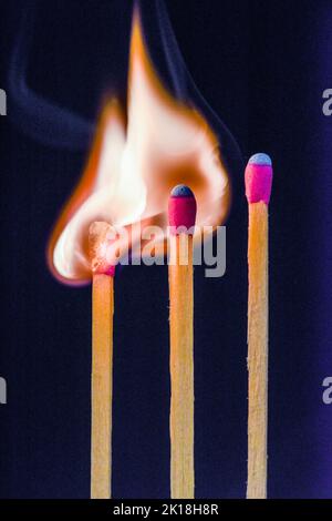 Tre partite, una che cattura il fuoco dall'altra. Concetto: Lavoro di squadra, sinergia o ispirazione. Foto Stock