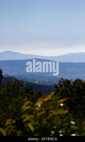 Uno scatto verticale delle montagne e delle turbine eoliche sullo sfondo del cielo blu. Foto Stock