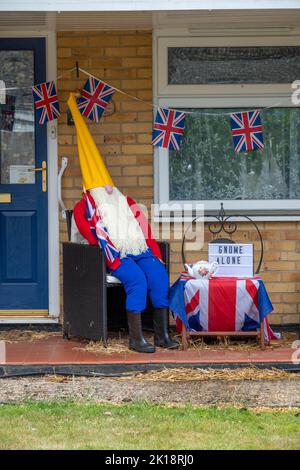 scarecrow vestito come gnome che tiene la bandiera di Union jack in celebrazione del Giubileo di platino della Regina e segno solo gnome Foto Stock