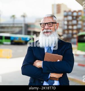 Felice uomo d'affari senior che tiene un tablet mentre aspetta nella stazione degli autobus Foto Stock