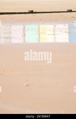 Riflessi di capanne multicolore sulla sabbia bagnata a Walton sulla spiaggia di Naze a Essex, Regno Unito Foto Stock