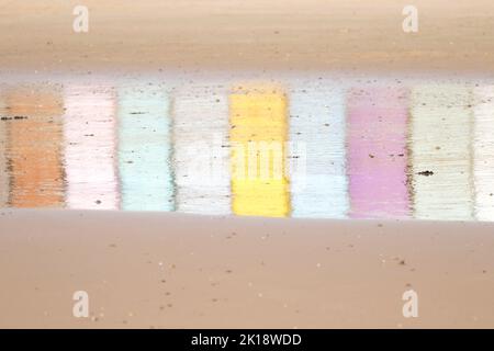 Riflessi di capanne multicolore sulla sabbia bagnata a Walton sulla spiaggia di Naze a Essex, Regno Unito Foto Stock