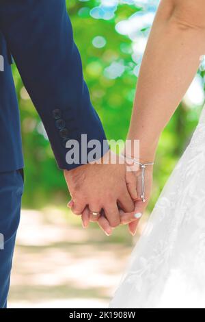 Giovane sposato fresco che tiene le mani l'un l'altro Foto Stock