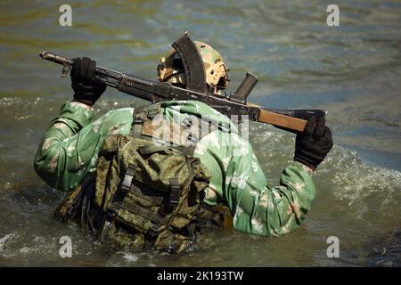 Esperienza militare completa - un giorno commando - correre attraverso l'acqua con la replica automatica del fucile Foto Stock