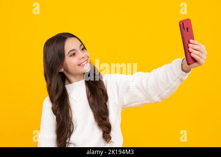 Ragazza adolescente utilizzare smartphone, condividere i social media, chattare da telefono cellulare indossare abiti eleganti casual alla moda isolato su sfondo giallo. Bambino Foto Stock