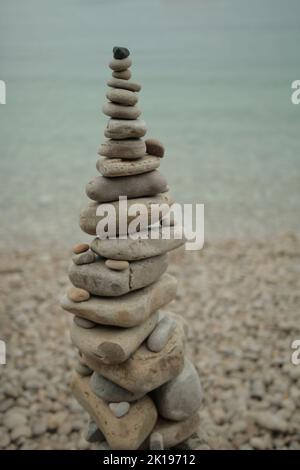 Cairn si trova su una spiaggia di ciottoli vicino all'acqua Foto Stock