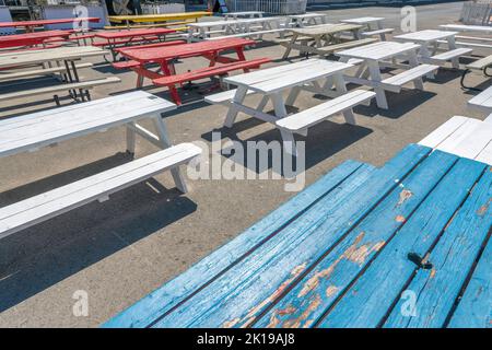 San Antonio, Texas - tavolo da pranzo in legno dipinto di blu, rosso, giallo, bianco con sedie. Tavoli in legno con posti a sedere su un terreno in cemento. Foto Stock