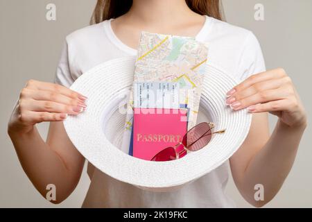 Viaggio internazionale. Viaggio di vacanza. Donna turistica in possesso di passaporto biglietto aereo viaggio guida mappa occhiali da sole in cappello di paglia isolato su backgro neutro Foto Stock