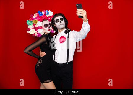 Foto di mostro spettrale coppia uomo donna abbraccio tenere telefono fare tema selfie immagine indossare breve mini nero abito morte fascia costume roses Foto Stock