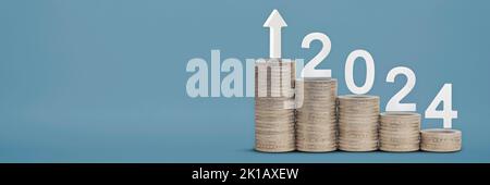 Felice anno nuovo 2024. Tema finanziario, pile di monete impilate in ordine crescente, come un grafico, su sfondo blu. Progettare per un calendario o. Foto Stock