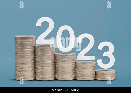 Felice anno nuovo 2023. Tema finanziario, pile di monete impilate in ordine crescente, come un grafico, su sfondo blu. Progettare per un calendario o. Foto Stock