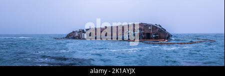 Un colpo panoramico di una petroliera affondata al largo della costa, catastrofe ecologica Foto Stock