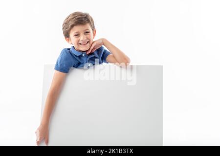 Sorridente ragazzo caucasico che mostra un poster pubblicitario bianco con spazio per il testo, su sfondo bianco. Foto Stock