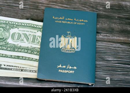 Passaporto egiziano con dollari americani di 1 $ uno banconote in denaro degli Stati Uniti isolato su sfondo di legno, Repubblica araba d'Egitto passaporto con Foto Stock