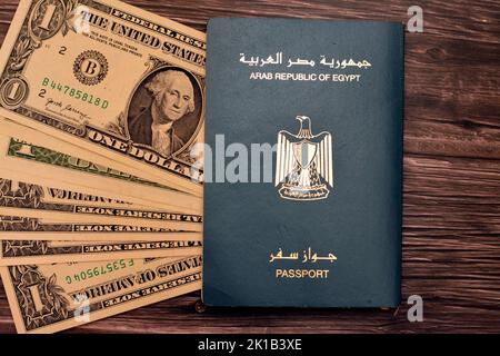 Passaporto egiziano con dollari americani di 1 $ uno banconote in denaro degli Stati Uniti isolato su sfondo di legno, Repubblica araba d'Egitto passaporto con Foto Stock