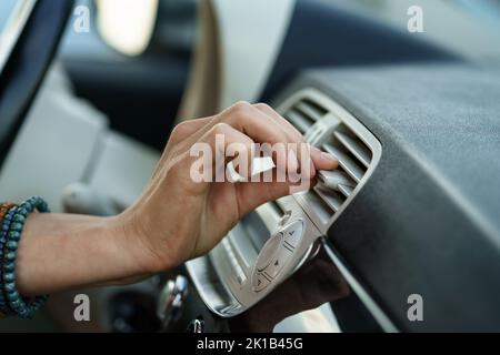 Donna mette mano sul pannello di ventilazione per controllare il flusso d'aria fredda seduto al sedile del conducente in auto nelle calde giornate estive Foto Stock