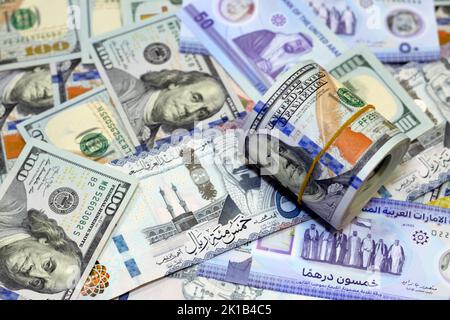 Rotolo di denaro americano con una banda su un mucchio di banconote in dollari americani banconote in contanti americani con Arabia Saudita riyals banconote in denaro e New Emir Foto Stock