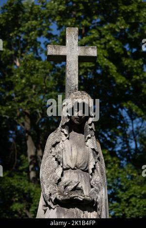 Santa Maria con scultura a croce cimitero, antica statua in necropoli storica. Foto Stock