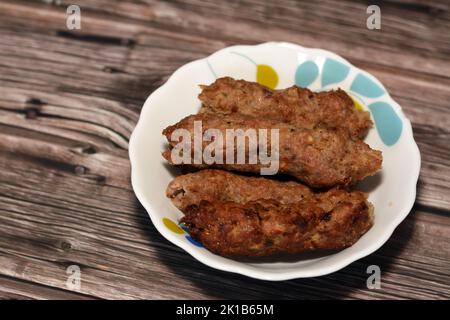 Cucina araba tradizionale cibo di manzo Kofta, kebab e tarb kofta che è carne macinata avvolto in carbone grasso di agnello alla griglia e servito su piatto profondo, Foto Stock