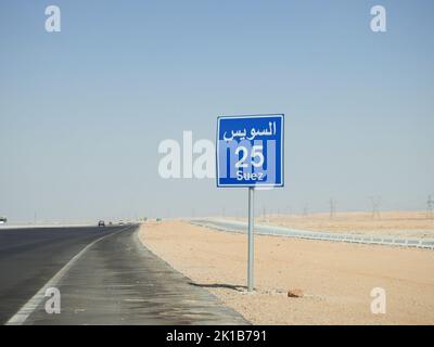 Suez, Egitto, 12 2022 agosto: Un cartello stradale in Suez Cairo autostrada dà la distanza restante a Suez città 25 KM venticinque chilometri scritto in Foto Stock