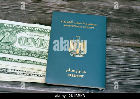 Passaporto egiziano con dollari americani di 1 $ uno banconote in denaro degli Stati Uniti isolato su sfondo di legno, Repubblica araba d'Egitto passaporto con Foto Stock