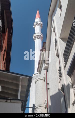 Pristina, Kosovo - 5 giugno 2022: Vista del Minareto alla moschea. Vista del Minareto tra gli edifici. Foto Stock