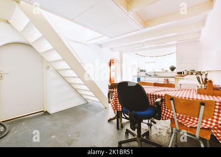 Tavolo e sedie si trovano sotto la lampada luminosa vicino alla pianta in vaso e foto in spaziosa sala da pranzo a casa Foto Stock