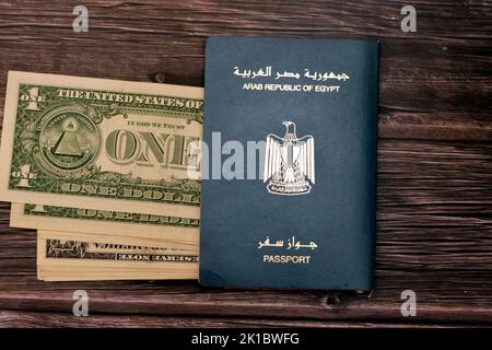 Passaporto egiziano con dollari americani di 1 $ uno banconote in denaro degli Stati Uniti isolato su sfondo di legno, Repubblica araba d'Egitto passaporto con Foto Stock