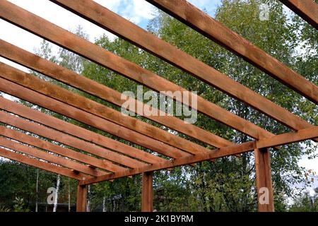 Il processo di costruzione di un baldacchino di legno dalle tavole marroni nella campagna in giorno di estate Foto Stock