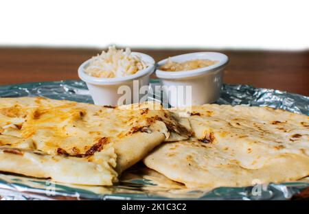 Primo piano di deliziose pupusas salvadorane con formaggio servito sul tavolo. Pupusas tradizionale servito con insalata sul tavolo. Due pupupe nicaraguane Foto Stock