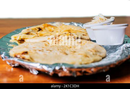 Pupusas tradizionale servito con insalata sul tavolo. Due pupusas Nicaraguane con insalata sul tavolo, vista laterale di deliziose pupusas Salvadoran con Foto Stock