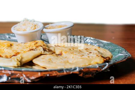 Due pupusas tradizionali servite con insalata sul tavolo. Due pupusas Nicaraguane con insalata isolata, vista laterale di deliziose pupusas Salvadoran con Foto Stock