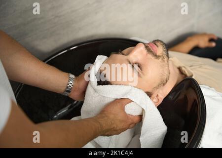 Uomo soddisfatto con capelli appena lavati e asciugati al barbiere Foto Stock