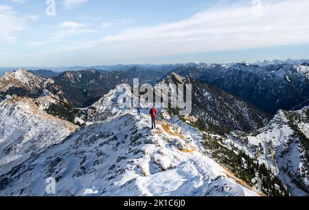 Arrampicatori sulla stretta cresta rocciosa innevata del Hochplatte Ammergauer, vista verso Loesertaljoch, vista del panorama di montagna, escursioni al Foto Stock