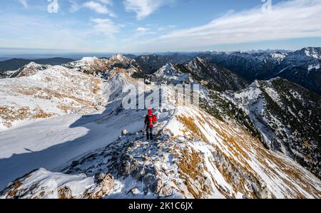 Arrampicatori sulla stretta cresta rocciosa innevata del Hochplatte Ammergauer, vista verso Loesertaljoch, vista del panorama di montagna, escursioni al Foto Stock